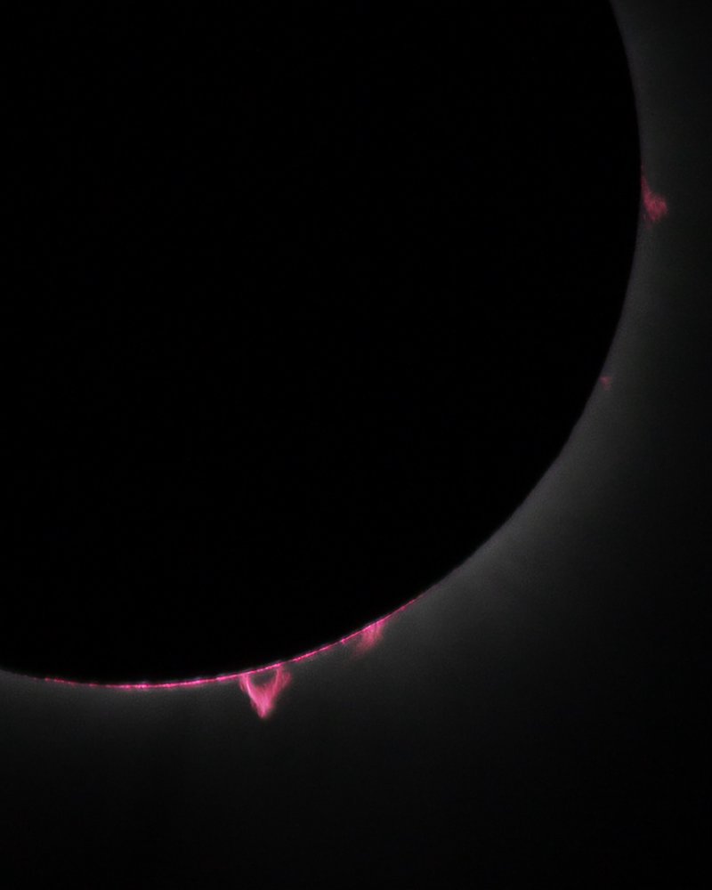 Solar prominences peeking out from behind the moon. Photo of solar prominences visible during the eclipse